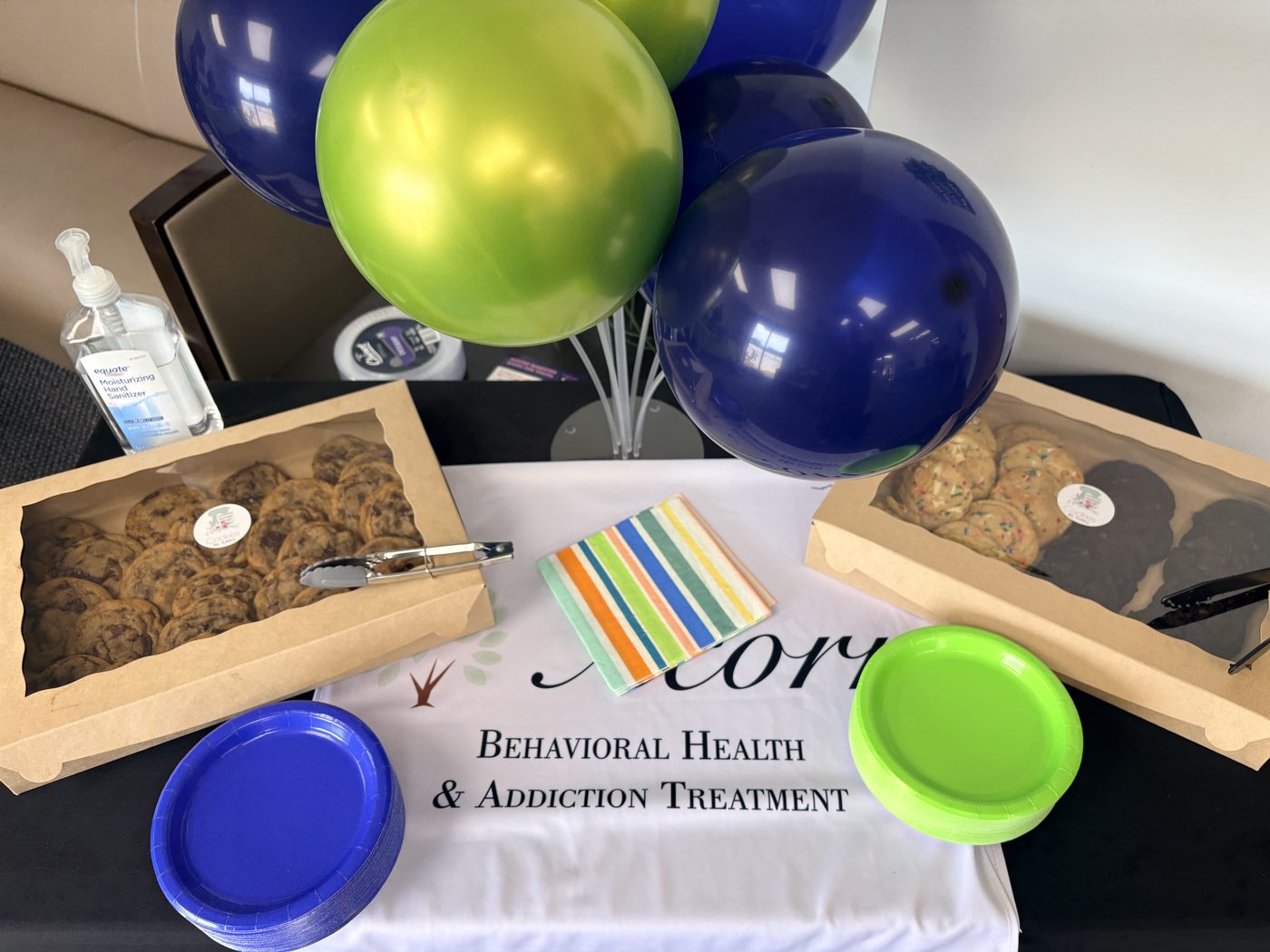 Boxes of Cookies by Ashley chocolate chip and funfetti cookies on the Acorn Behavioral Health tablecloth with balloons above