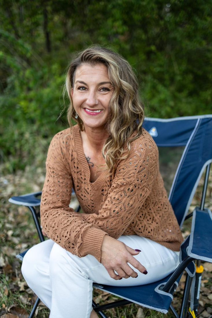 Jessica Newby smiling warmly, seated outdoors